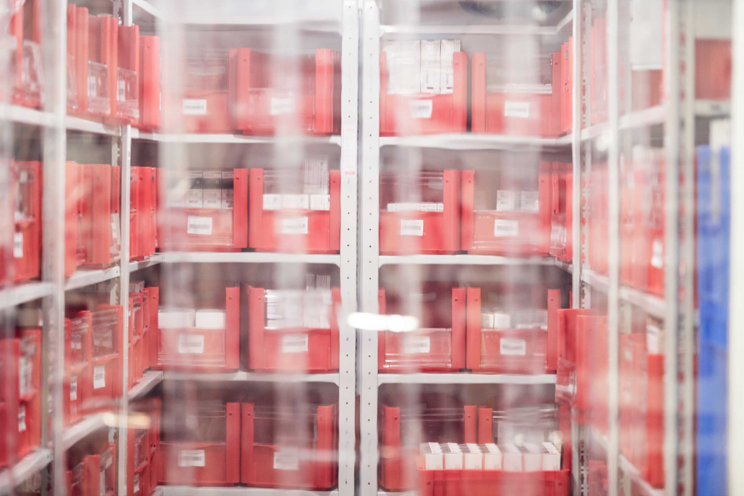 Mehrere Regale mit roten Boxen, die Arzneimittel enthalten, stehen dicht aneinander in einem Kühlraum.